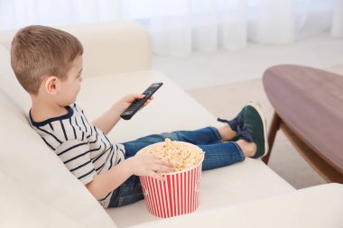 Küçük çocuk evde kanepede televizyon izlerken