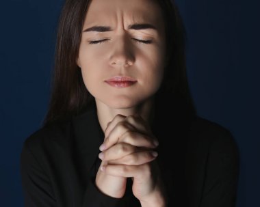 Koyu arka plan üzerinde dua dindar genç kadın