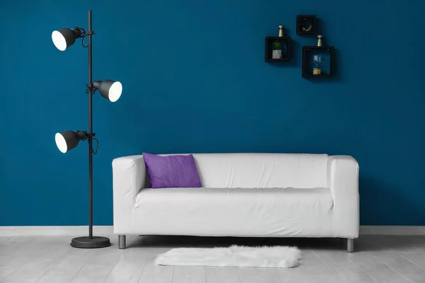 Beautiful sofa and lamp near color wall