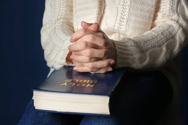 Religious young woman praying over Bible, closeup