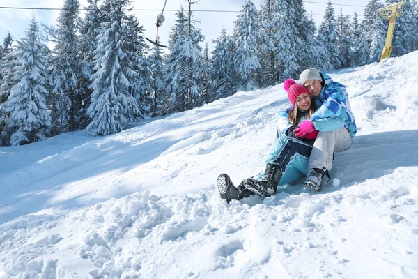 Mutlu çift Resort karda güneşli günde oturuyor. Kış tatili