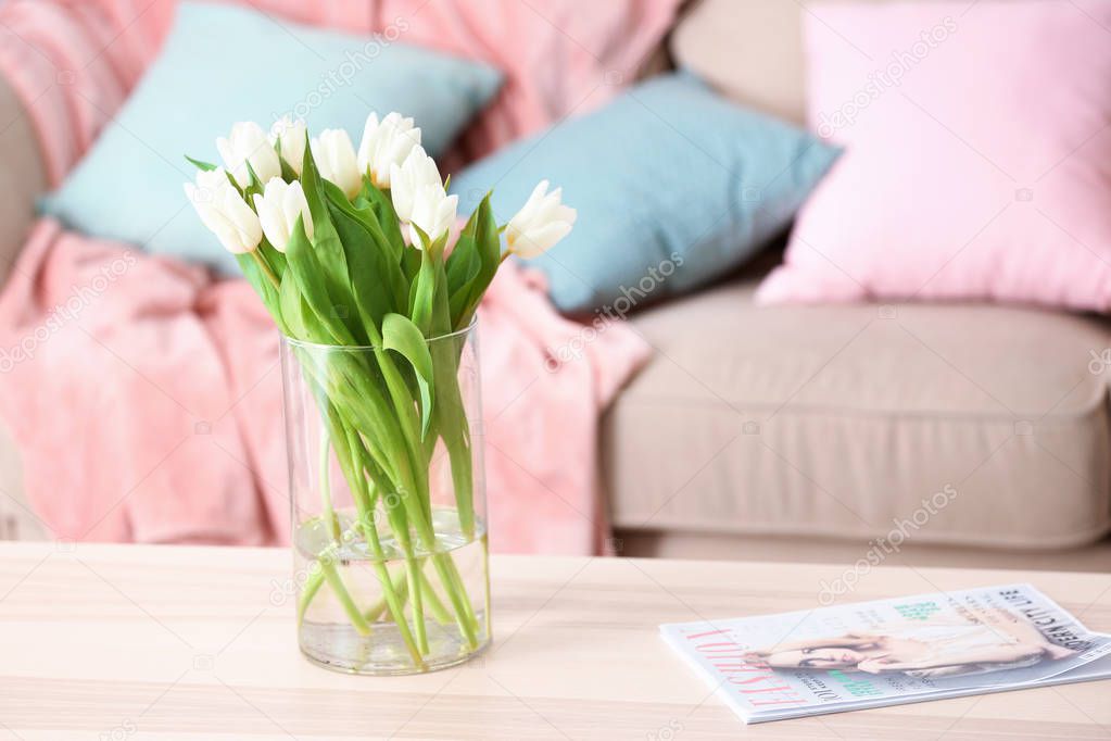 Wooden table with bouquet of tulips in living room