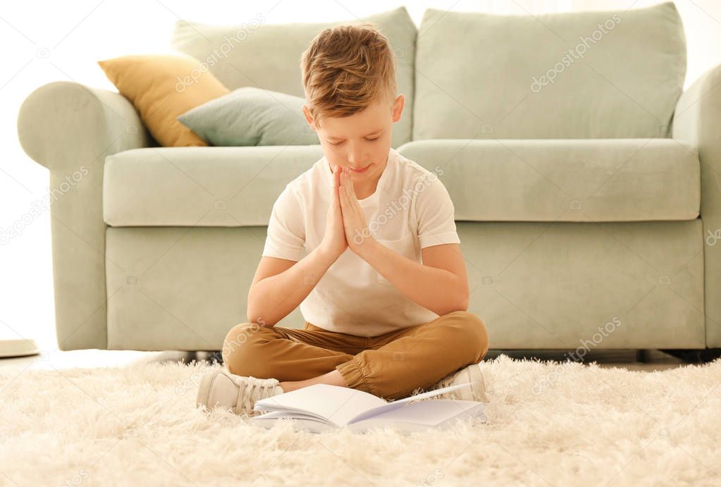 Religious little boy praying at home