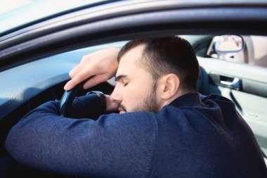 Genç adam arabanın içinde trafik sıkışıklığı sırasında uyku