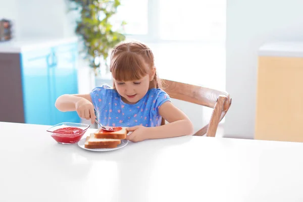 Little girl spreading jam on toast — Stock Photo, Image