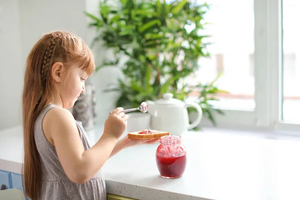 Gadis kecil menyebarkan selai di roti panggang — Stok Foto