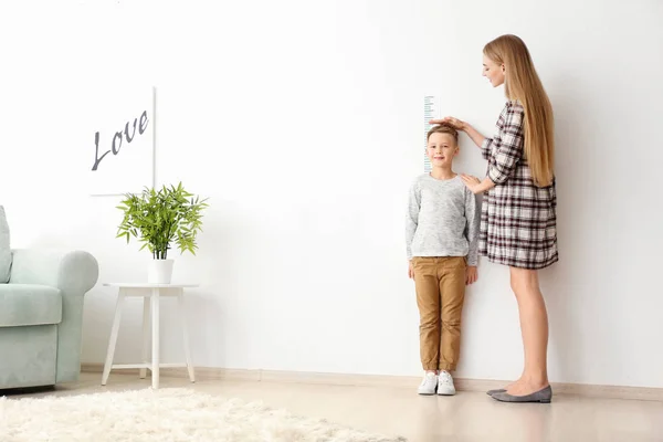 Mujer que mide la altura del niño — Foto de Stock