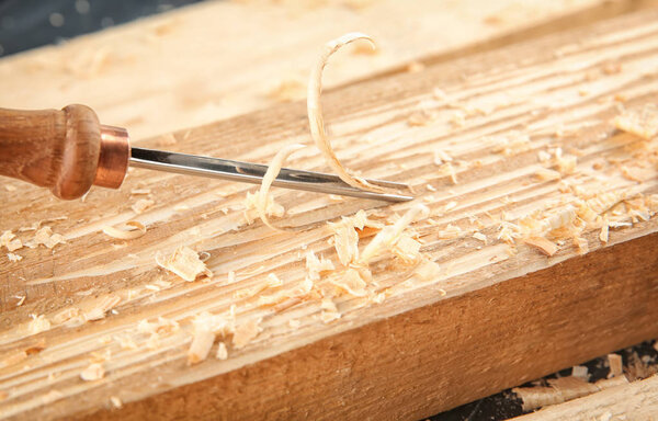 Chisel, wooden boards and sawdust in carpenter's workshop