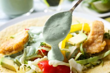 Balıklı taco, closeup üzerine lezzetli kremalı sos dökme