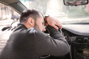Araba trafik sıkışıklığı sırasında yorgun genç adam