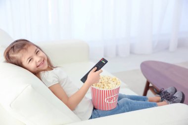 Küçük kız evde kanepede televizyon izlerken