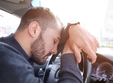 Genç adam arabanın içinde trafik sıkışıklığı sırasında uyku