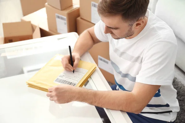 Young man preparing parcel envelopes — Stock Photo, Image