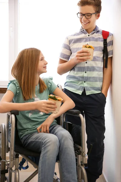 Mädchen im Rollstuhl mit Junge beim Sandwichessen — Stockfoto