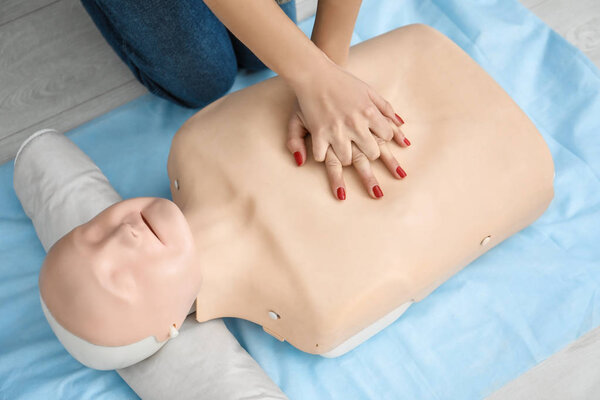 Женщина практикует искусственное дыхание на манекене в классе первой помощи
