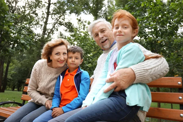 Senior Paar Hun Kleinkinderen Zittend Bankje Park — Stockfoto