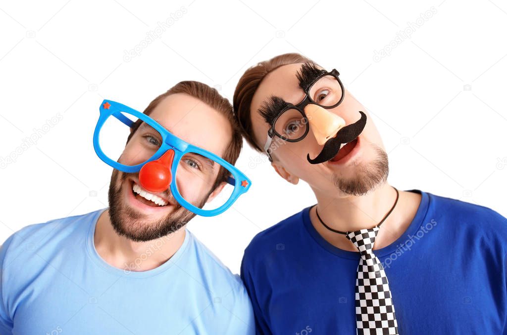 Young friends in funny disguise posing on light background. April fool's day celebration
