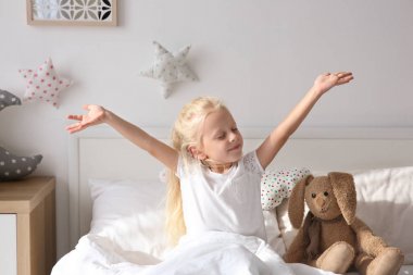 Sevimli küçük kız yatakta evde germe