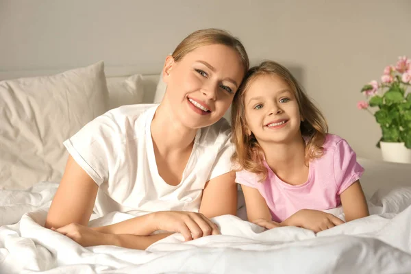 Happy mother and her daughter on bed in children room