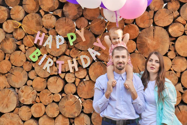 Junge Familie Mit Geburtstagskränzchen Und Luftballons Vor Holzhintergrund — Stockfoto