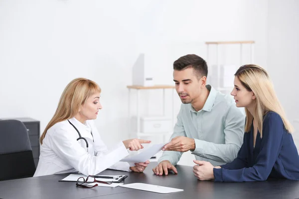 Doctora Consultando Pareja Joven Clínica —  Fotos de Stock