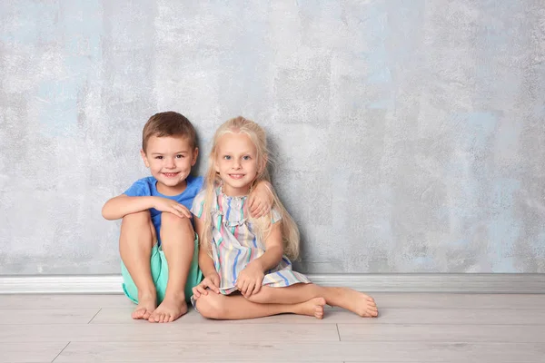 Gri Duvara Yakın Oturan Sevimli Küçük Çocuklar — Stok fotoğraf