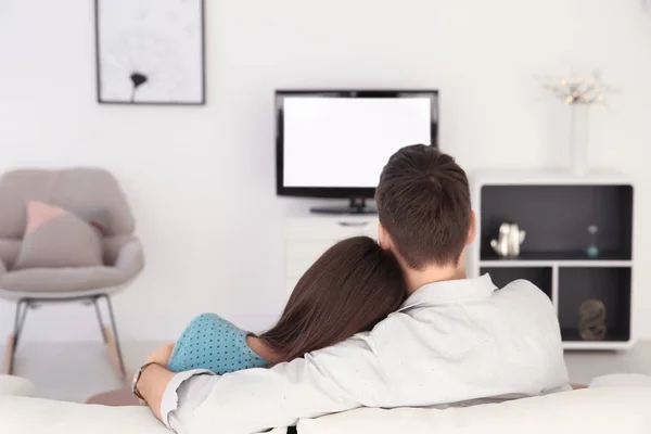 年轻的夫妇在家里的沙发上看电视 — 图库照片