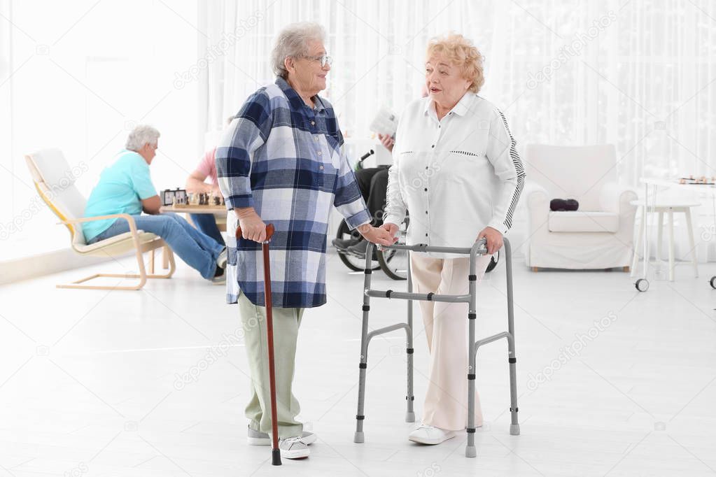 Senior women with walkers and cane talking at care home