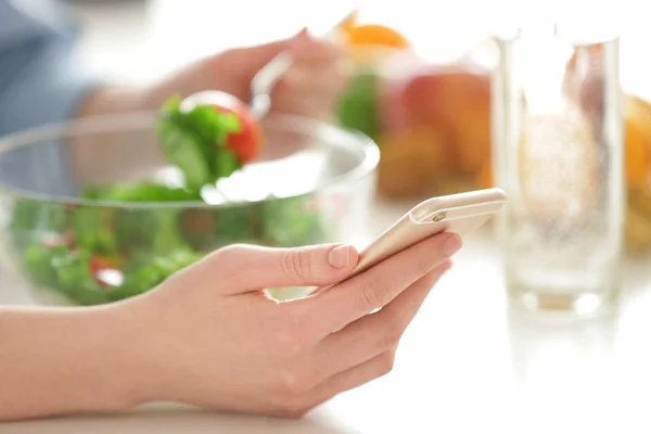 Woman counting calories while eating salad — Stock Photo, Image