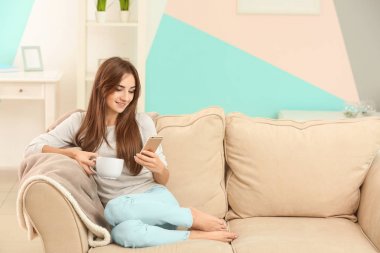 Genç kadın ile telefon ve çay evde kanepe