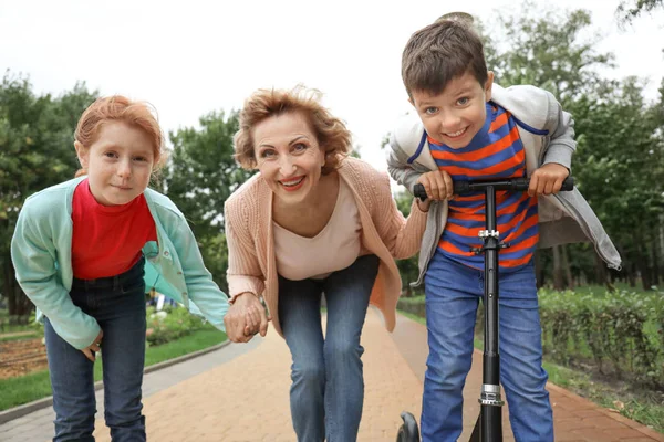 Park'ta dinlenme torunları ile üst düzey kadın — Stok fotoğraf