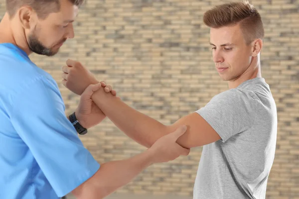 Fisioterapista che lavora con un giovane paziente in clinica — Foto Stock