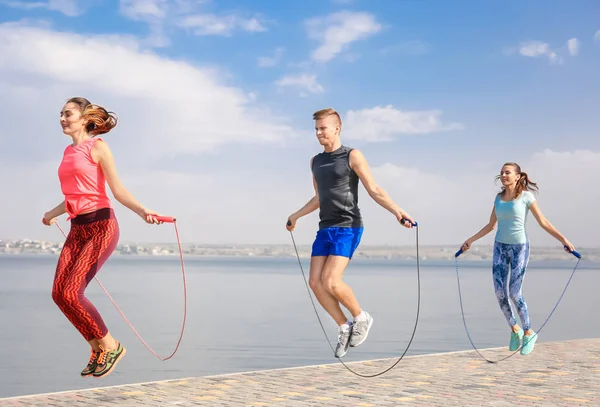 Young people with jumping ropes on quay