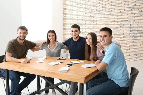 Jóvenes sentados a la mesa juntos —  Fotos de Stock