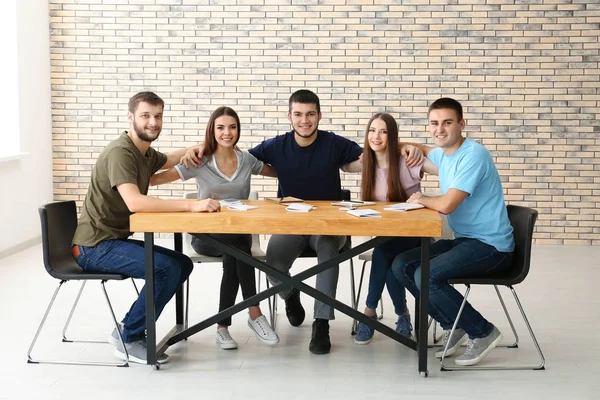 Jóvenes sentados a la mesa juntos — Foto de Stock