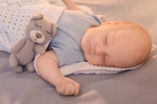 Słodkie maleństwo z zabawkami, spanie na łóżku — Zdjęcie stockowe