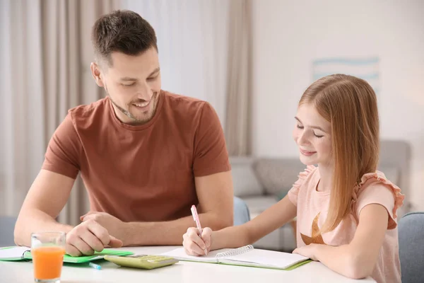 Cute little girl doing homework with father — Stock Photo, Image