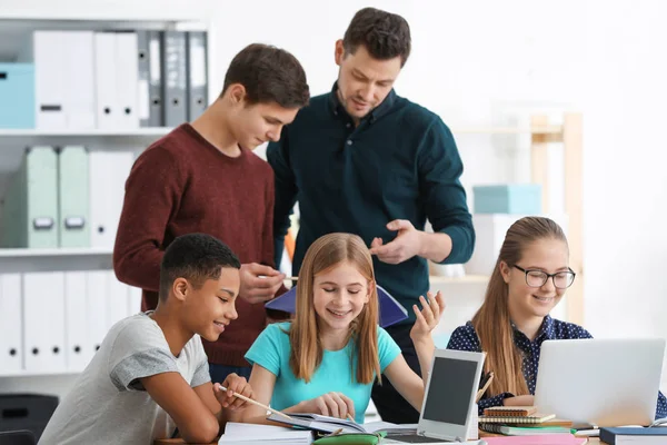 Teenagers doing homework with teacher — Stock Photo, Image