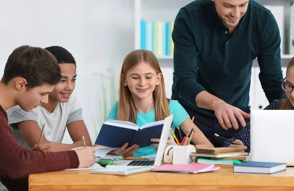 Adolescentes haciendo la tarea con el profesor — Foto de Stock