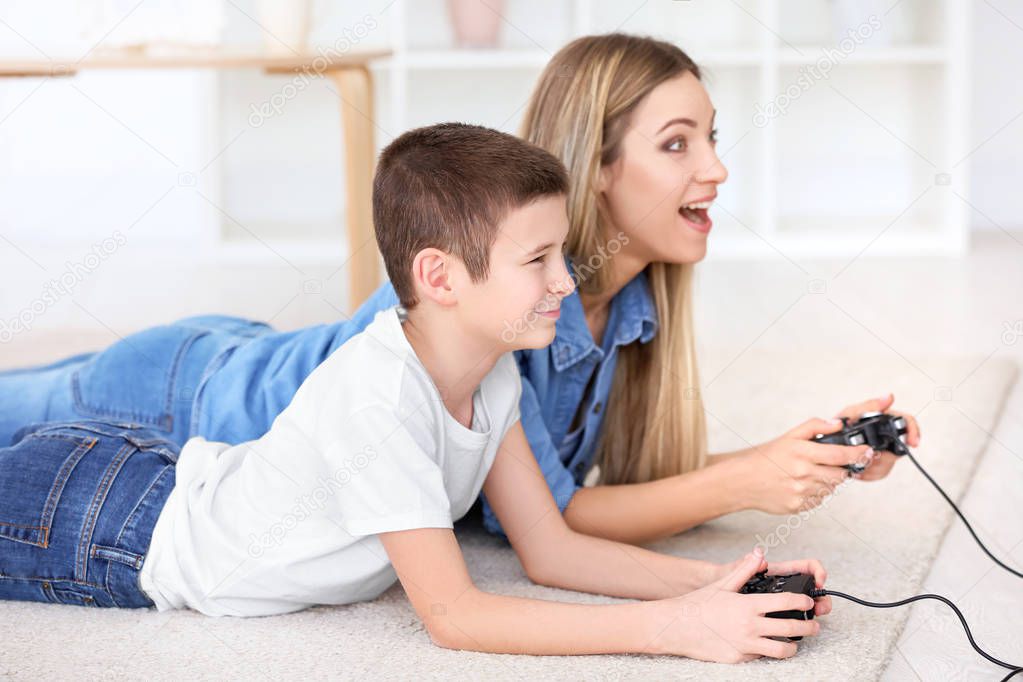 Young woman playing video games with her son at home