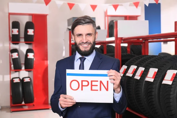 manager holding sign in car store