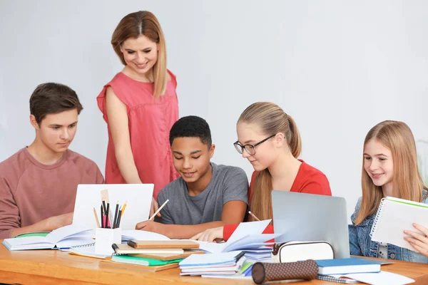 Adolescentes haciendo la tarea con el profesor —  Fotos de Stock