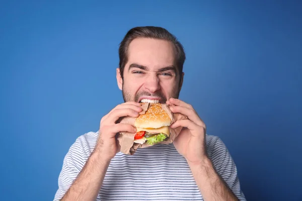 Красивый мужчина ест вкусный бургер — стоковое фото