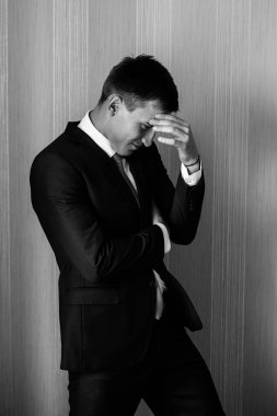 Alında bir el ile takım elbiseli bir adam yanında duruyor