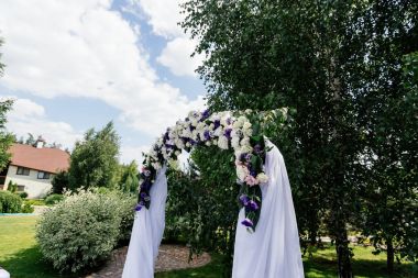 Çiçekler ve huş ağacı yakınındaki beyaz bez ile düğün kemer