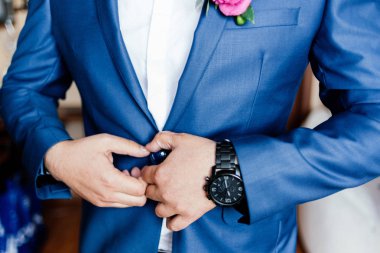 Damat belgili tanımlık düğme ceketini takılır.