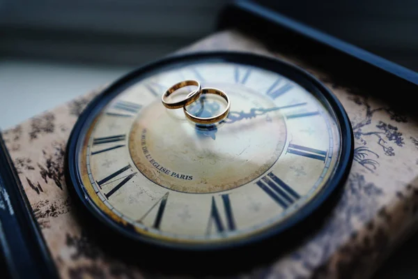 Anillos de boda de oro se encuentran en el reloj — Foto de Stock