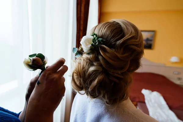 Cabeleireiro faz penteado para a noiva. Manhã de noiva. O cabeleireiro decora o cabelo da noiva com flores frescas — Fotografia de Stock