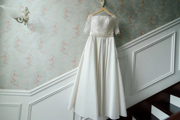 Vestido de noiva pendurar na lâmpada contra a parede ao lado das escadas do hotel — Fotografia de Stock