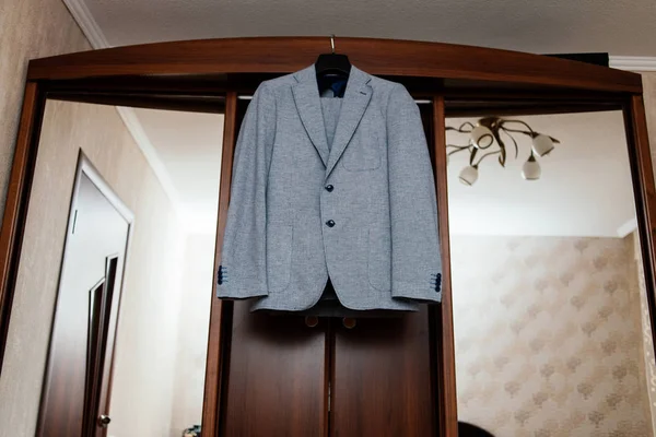 Красивый серый костюм жениха висит на шкафу в комнате — стоковое фото